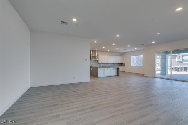 unfurnished living room featuring plenty of natural light, light hardwood / wood-style floors, and sink