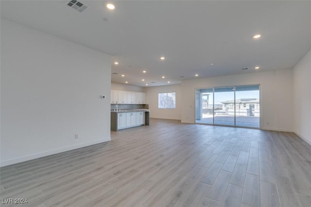 unfurnished living room with sink and light hardwood / wood-style floors