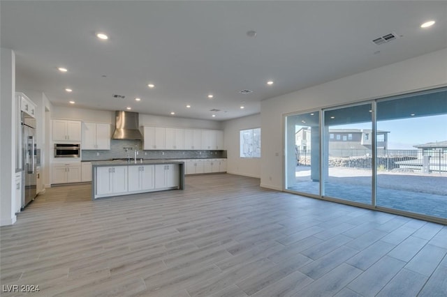 kitchen with white cabinetry, a wealth of natural light, stainless steel appliances, and wall chimney range hood