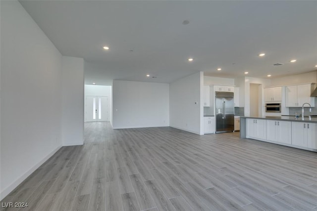 unfurnished living room with light hardwood / wood-style flooring and sink