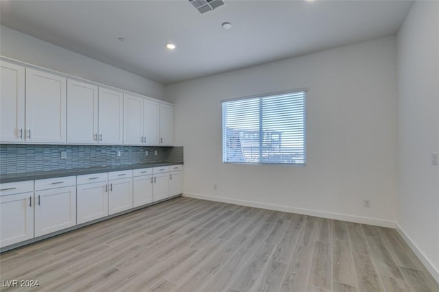 kitchen with tasteful backsplash, white cabinetry, and light hardwood / wood-style flooring