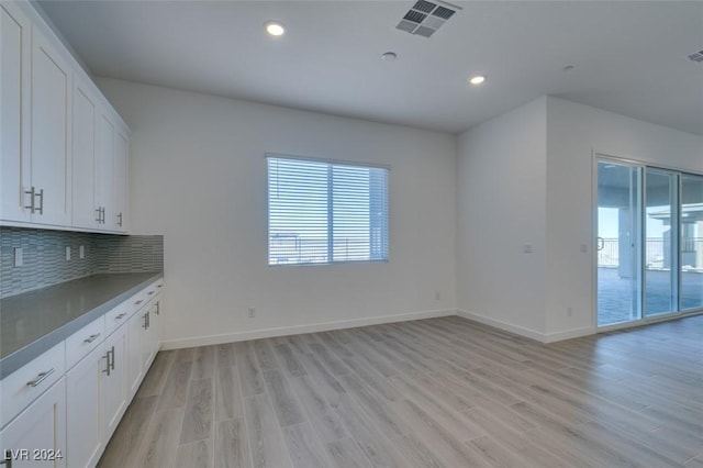 interior space with decorative backsplash, white cabinets, and light wood-type flooring