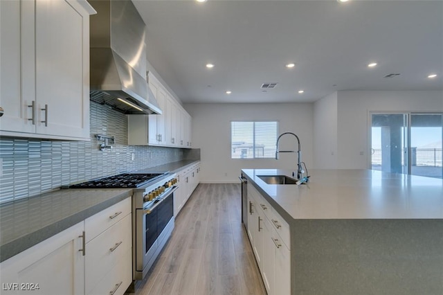 kitchen with white cabinetry, sink, wall chimney exhaust hood, and high end stainless steel range oven