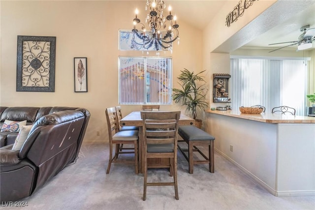 carpeted dining space featuring ceiling fan with notable chandelier and lofted ceiling