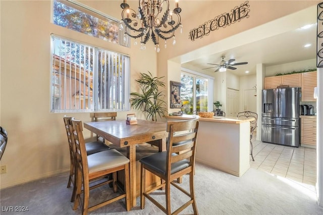 carpeted dining space with ceiling fan with notable chandelier