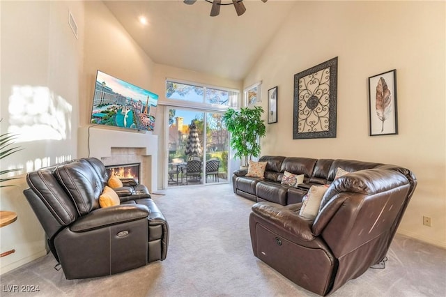 living room with a tiled fireplace, light carpet, high vaulted ceiling, and ceiling fan