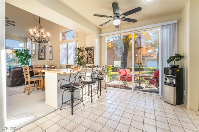 kitchen with a kitchen breakfast bar, light tile patterned floors, pendant lighting, and ceiling fan with notable chandelier