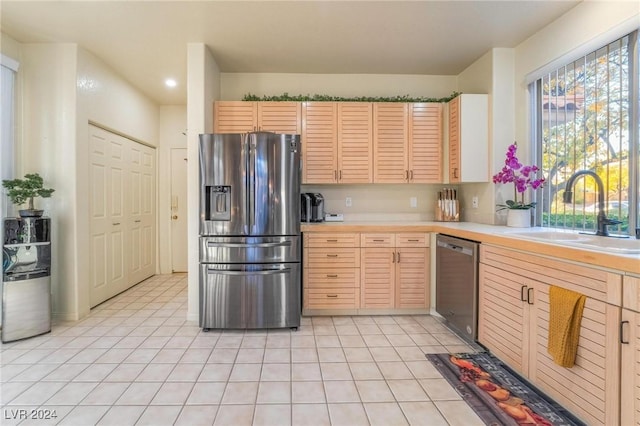 kitchen featuring light brown cabinetry, sink, light tile patterned floors, and appliances with stainless steel finishes