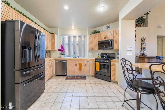 kitchen featuring sink, light tile patterned flooring, black appliances, and light brown cabinets