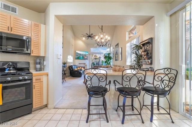 kitchen featuring black gas stove, light colored carpet, plenty of natural light, and light brown cabinetry