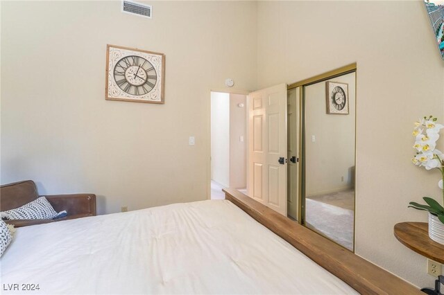 carpeted bedroom with a closet and a towering ceiling