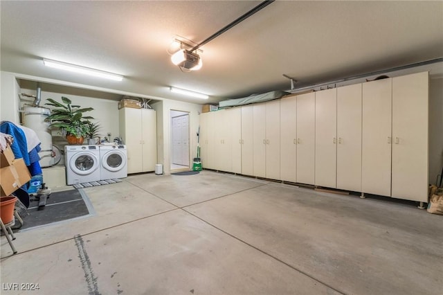 garage with secured water heater, washer and clothes dryer, and a garage door opener