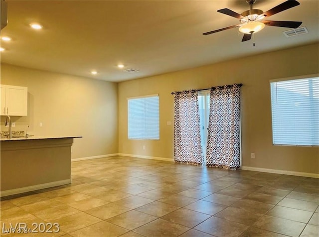 unfurnished living room with ceiling fan, sink, and light tile patterned floors