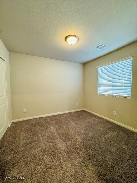 carpeted empty room with a textured ceiling