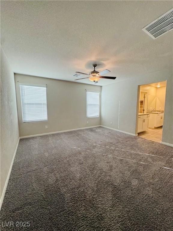 spare room featuring ceiling fan, light carpet, and a textured ceiling