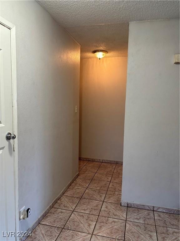 hallway with light tile patterned floors and a textured ceiling