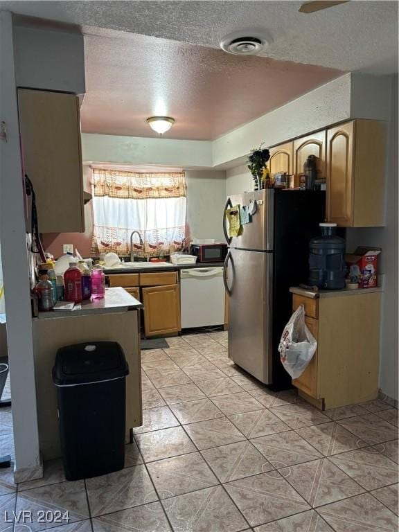 kitchen with visible vents, freestanding refrigerator, a sink, a textured ceiling, and dishwasher