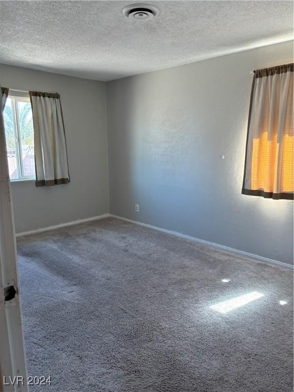 unfurnished room featuring baseboards, visible vents, carpet floors, and a textured ceiling