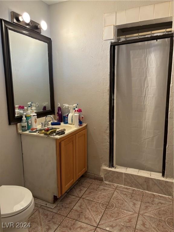 bathroom featuring vanity, a shower stall, toilet, and tile patterned flooring