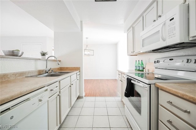 kitchen with white appliances, sink, decorative light fixtures, white cabinets, and light tile patterned flooring