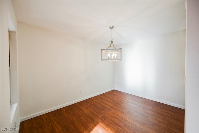 spare room featuring dark hardwood / wood-style flooring and a chandelier