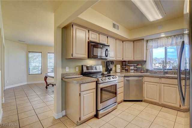 kitchen with light brown cabinetry, light tile patterned floors, and appliances with stainless steel finishes