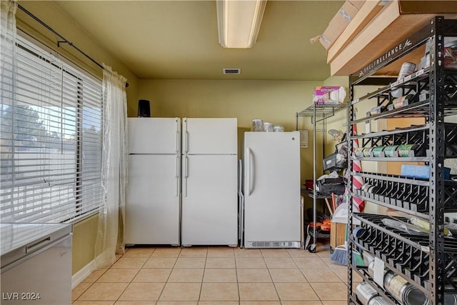 kitchen with white cabinets, light tile patterned floors, and white refrigerator