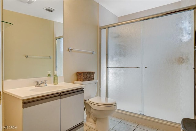 bathroom featuring tile patterned flooring, vanity, a shower with shower door, and toilet