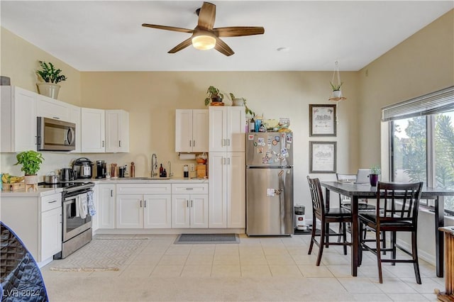 kitchen featuring ceiling fan, sink, white cabinets, and stainless steel appliances