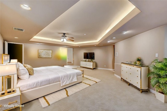 carpeted bedroom featuring a tray ceiling and ceiling fan