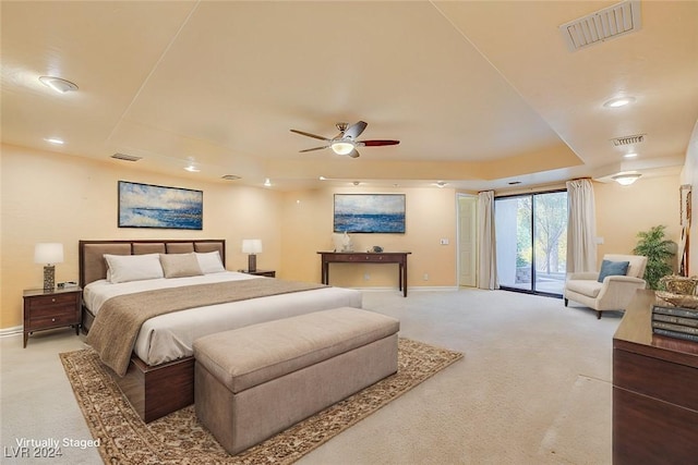 carpeted bedroom with ceiling fan, a raised ceiling, and access to outside