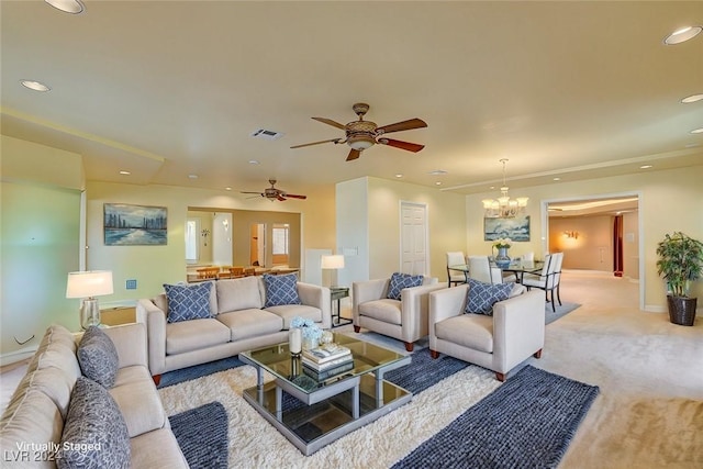 living room with ceiling fan with notable chandelier and light carpet