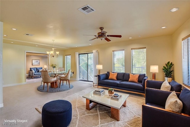 carpeted living room featuring ceiling fan with notable chandelier