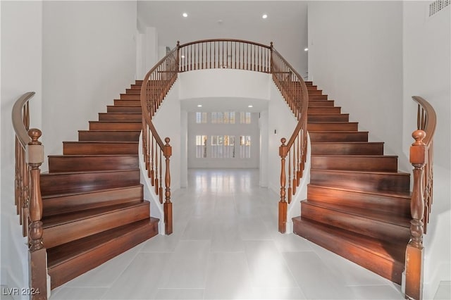 stairway featuring tile patterned flooring and a towering ceiling