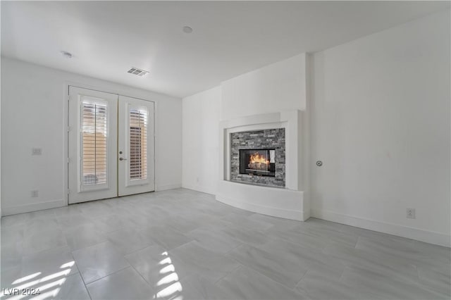 unfurnished living room featuring a fireplace and french doors