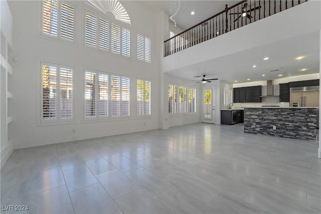 tiled living room with a high ceiling, ceiling fan, and sink