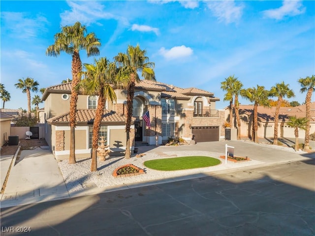 mediterranean / spanish-style home with central air condition unit and a garage