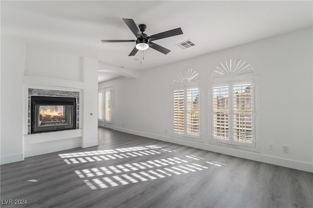 unfurnished living room featuring a multi sided fireplace, ceiling fan, and dark wood-type flooring