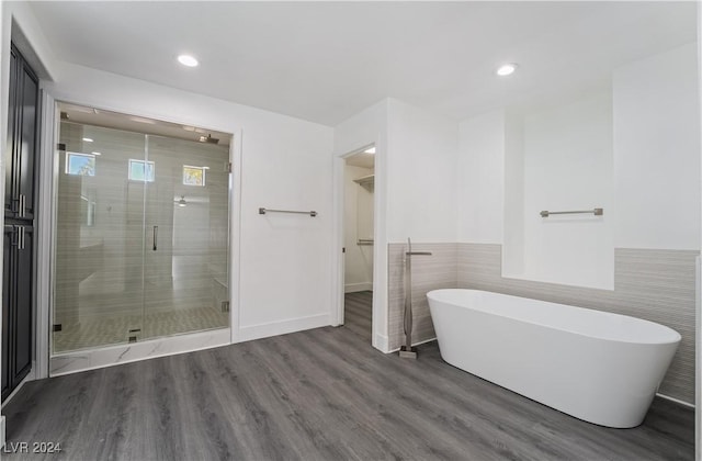 bathroom featuring independent shower and bath, wood-type flooring, and tile walls