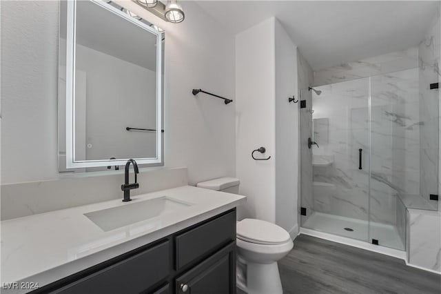 bathroom with hardwood / wood-style floors, vanity, toilet, and walk in shower