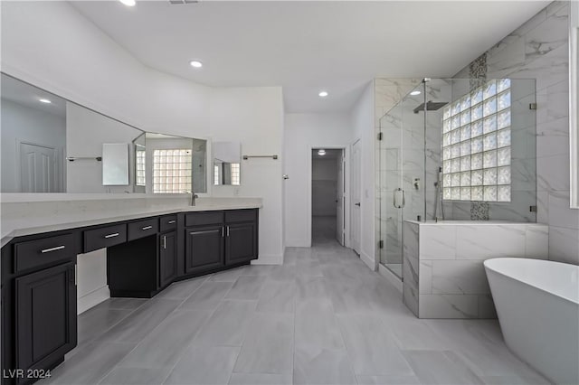 bathroom featuring plus walk in shower, tile patterned flooring, vanity, and a healthy amount of sunlight