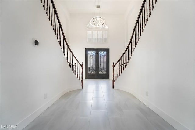 foyer with french doors, light tile patterned floors, and a high ceiling