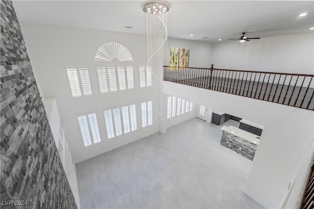 hallway featuring a healthy amount of sunlight, a towering ceiling, and a chandelier