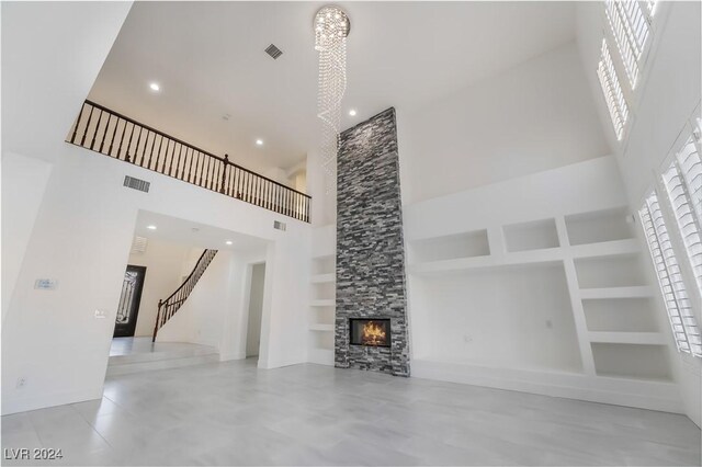 unfurnished living room featuring built in shelves, a fireplace, and a towering ceiling