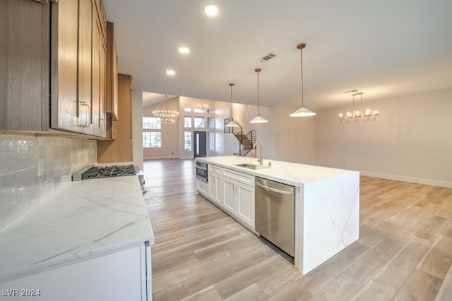 kitchen with hanging light fixtures, light wood-type flooring, appliances with stainless steel finishes, light stone counters, and white cabinetry