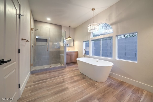 bathroom with vanity, lofted ceiling, an inviting chandelier, hardwood / wood-style flooring, and separate shower and tub