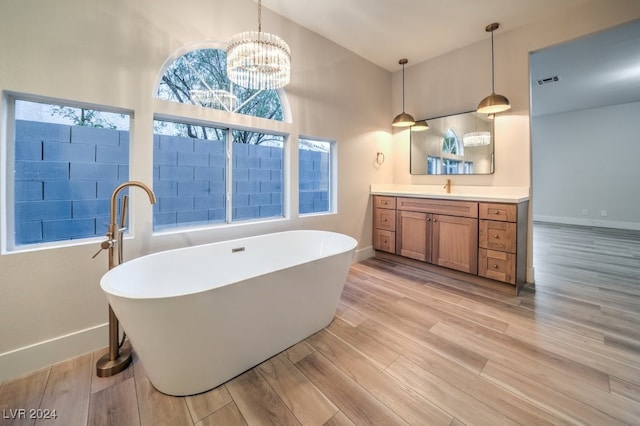 bathroom with vanity, vaulted ceiling, a tub to relax in, a notable chandelier, and wood-type flooring