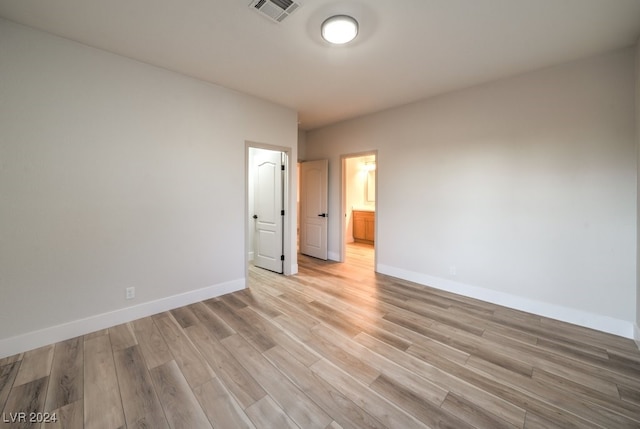 unfurnished bedroom with ensuite bath and light hardwood / wood-style floors