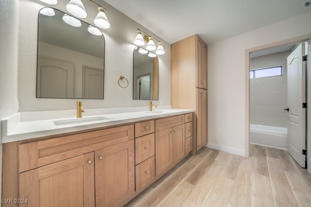 bathroom featuring hardwood / wood-style flooring, vanity, and washtub / shower combination