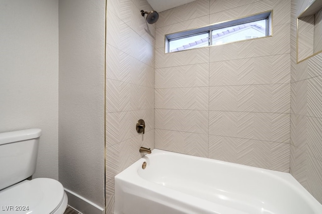 bathroom with tiled shower / bath combo and toilet